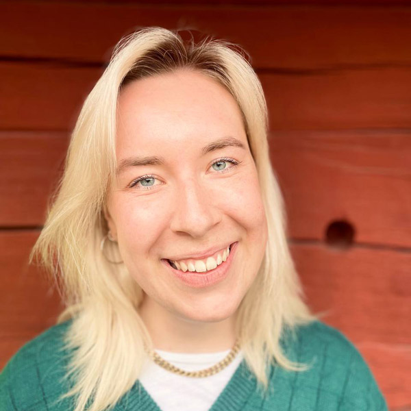 Portrait Person weiblich gelesen, weiß, mittellange blonde Haare lächelnd, grüner Pulli